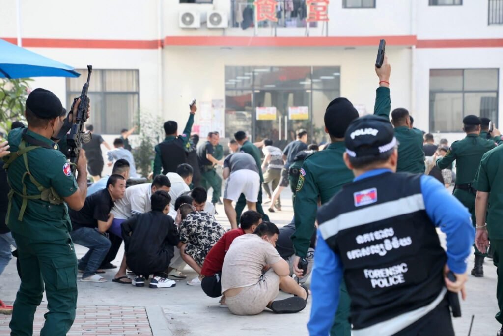 Police personnel oversee the movement of detainees during searches across multiple buildings of the Wan Cheng (A7) complex.